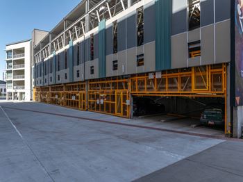A large building with a grey and white exterior and a yellow support structure.